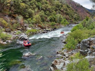 View of Trinity River with rafts full of people navigating the rapids