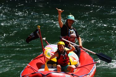 Rafting Guide and kid giving thumbs up on red raft in river